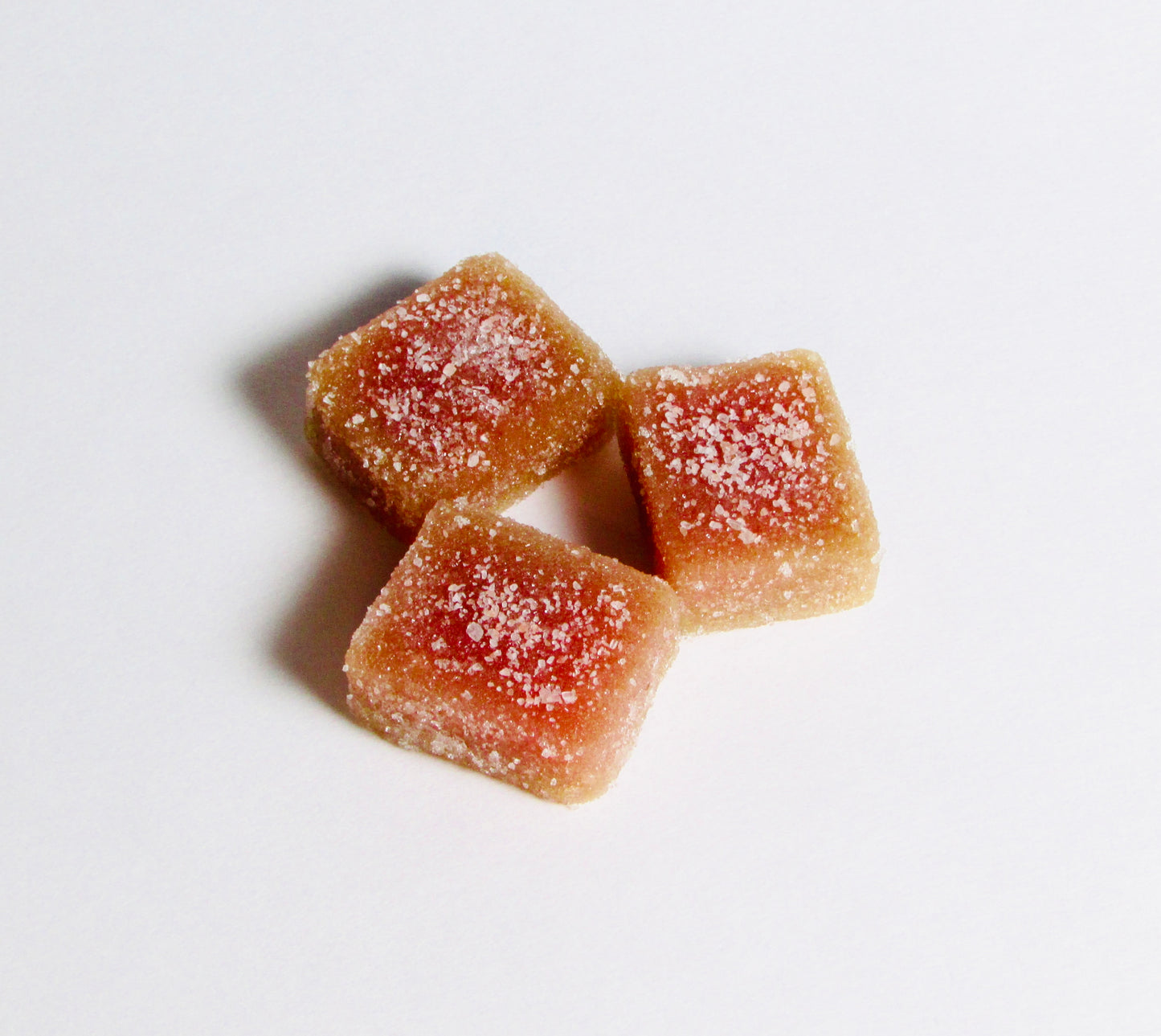 Three square-shaped gummy candies with a white background
